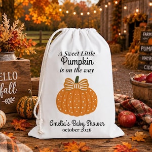 Könnte beinhalten: Ein weißer Kordelzugbeutel mit einer Grafik eines orangefarbenen Kürbisses mit Schleife, bedruckt mit dem Text A Sweet Little Pumpkin is on the way, Amelia's Baby Shower und october 2026 in schwarzer Schrift mit weißem Kordelverschluss.