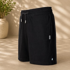 May include: Black shorts featuring an elastic waistband with a black drawstring and silver-toned metal aglets. A small rectangular black label with the white text NADS is sewn onto the side seam, and a tiny light blue tag is at the bottom hem.