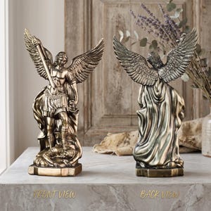 May include: A bronze-toned statue of an archangel with large wings, wearing armour and holding a sword while standing over a figure. The statue is shown from both the front and back views, with the text FRONT VIEW and BACK VIEW printed below.