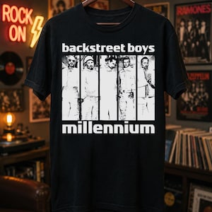 May include: A black short-sleeve t-shirt featuring a white graphic print of the Backstreet Boys. The design includes five vertical panels showing the band members, with the text "backstreet boys" above and "millennium" below the images.