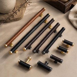 Puede incluir: Una colección de herrajes para muebles que incluye tiradores largos y pomos en forma de T. Cada pieza presenta una superficie texturizada con aspecto trenzado en negro, marrón oscuro o beige, con remates y soportes metálicos dorados o grises.