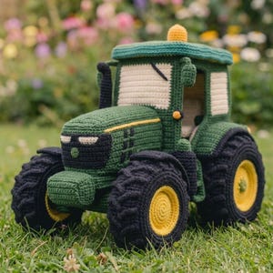 May include: A crocheted toy tractor featuring a dark green body with black tyres, yellow wheel centres, and cream-coloured windows. The tractor includes a black exhaust pipe, a small yellow roof light, and a detailed front grille design.