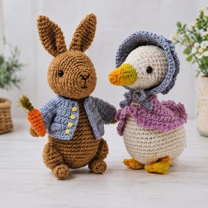 May include: A brown crocheted rabbit wearing a light blue jacket with yellow buttons and holding an orange carrot, standing next to a white crocheted duck wearing a blue bonnet and a purple cape with yellow feet and an orange beak.