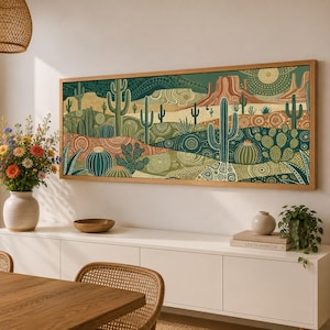 May include: A rectangular wall art piece featuring a desert landscape with various cacti, mesas, and a sun, rendered in a dot-art style with shades of green, tan, and brown, enclosed in a light wood frame and displayed above a white sideboard.