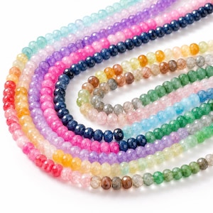 May include: A collection of multi-coloured faceted round beads arranged in concentric circular strands. The beads feature a translucent finish and a wide spectrum of colours including red, orange, yellow, green, blue, purple, and pink.