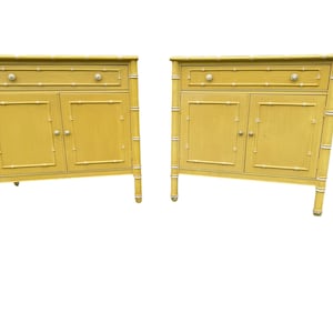 May include: Two matching yellow cabinets with bamboo-style frames. Each cabinet has a drawer, two doors, and silver-colored hardware. The cabinets are on four legs and have white accents.