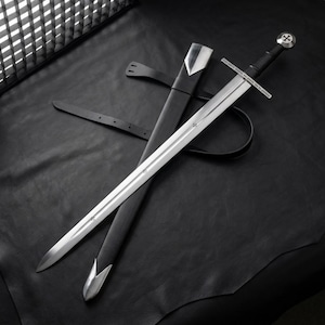 May include: A steel longsword with a straight crossguard, a black leather-wrapped grip, and a circular pommel featuring a cross emblem. The sword is accompanied by a black leather scabbard with silver-toned metal fittings at the tip and throat.