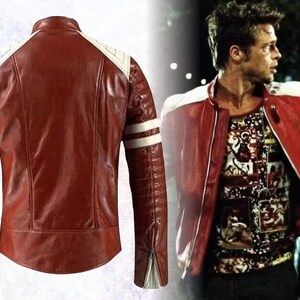 May include: A red leather jacket featuring white shoulder panels and double white stripes on the sleeves. The jacket has a stand-up collar, vertical seam detailing on the back, and zippered cuffs with white gussets, shown alongside a movie still.