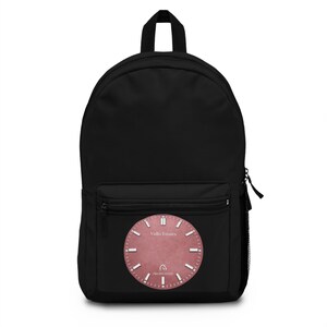 May include: A black backpack featuring a circular, dusty rose-coloured graphic on the front pocket. The graphic displays a clock face design with white hour markers, the text "Vullo Estates" at the top, and a small horse logo above "PRIVATE ESTATE".