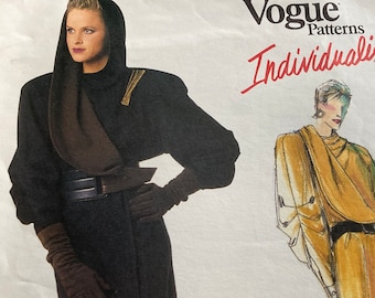 May include: Vogue Patterns Individualist fashion illustration. A woman is wearing a black hooded coat with a brown scarf, a wide black belt, and brown gloves. The coat has gold accents. A second illustration shows a yellow draped garment.
