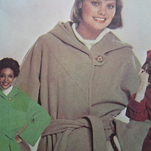 Può includere: Immagine di un modello di cucito vintage con cappotti con cappuccio in vari colori. Il cappotto principale è marrone chiaro con cintura abbinata e ampio cappuccio. Altri cappotti sono verdi e rossi.