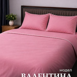 Può includere: Un set di biancheria da letto rosa a tinta unita composto da un copripiumino e due federe abbinate, ciascuna rifinita con un sottile bordo bianco. Il testo "модел ВАЛЕНТИНА" è stampato in bianco nell'angolo in basso a destra.