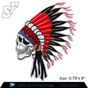 May include: An embroidered patch featuring a white skull wearing a large headdress with red and black feathers, a white band, and blue triangular accents. A circular emblem with a lightning bolt is on the side. The patch measures 11.75 inches by 8 inches.