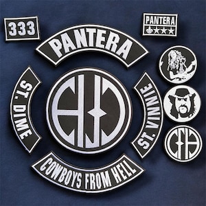 May include: A collection of black and white embroidered patches featuring the text Pantera, 333, St. Dime, St. Vinnie, and Cowboys From Hell. The set includes circular patches with band member portraits and logos, alongside curved rocker patches and rectangular designs.
