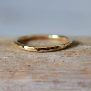 May include: A thin gold band ring with a hammered texture.