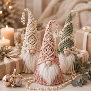 May include: Three decorative gnomes crafted with macrame cord in cream, dusty pink, and sage green. Each gnome features a wooden bead nose, a long white faux fur beard, and a tall pointed hat adorned with small white pearls and a tiny fabric bow.