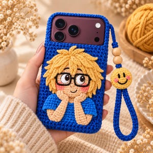 May include: A blue crochet phone case featuring a three-dimensional character with yellow hair, black glasses, and a blue shirt. The case includes a matching blue wrist strap adorned with two wooden beads and a yellow crocheted smiley face charm.