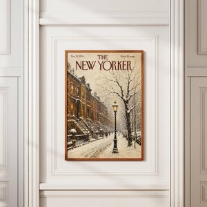 May include: A framed print of The New Yorker magazine cover dated Dec. 21, 1974, featuring a snowy city street scene with brownstone buildings, a lit street lamp, and bare trees under a winter sky, all enclosed in a simple wooden frame.