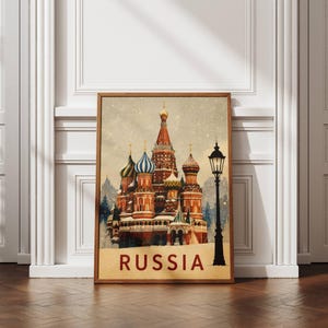 May include: A rectangular wall art print featuring Saint Basil's Cathedral with its iconic colorful onion domes in a snowy landscape. A black vintage-style street lamp stands to the right. The word RUSSIA is printed in bold red letters at the bottom.