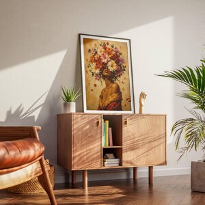 Black woman wall art featuring an elegant female portrait surrounded by a dramatic crown of colorful flowers in red, orange, cream and purple tones. Textured painterly artwork with a warm neutral background and rich botanical details. Perfect as floral woman art, feminine wall decor, African American art, boho portrait, bedroom artwork, living room decor or a colorful statement piece for a modern gallery wall.