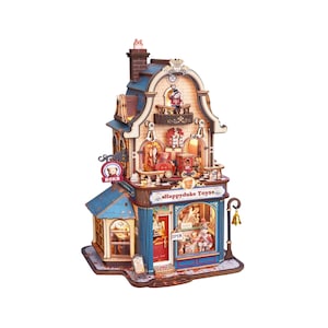 May include: A miniature wooden toy shop model titled Happyduke Toys with blue and brown architectural details, multiple levels, illuminated interior windows, a small balcony, a chimney, and a hanging gold bell on the exterior side.