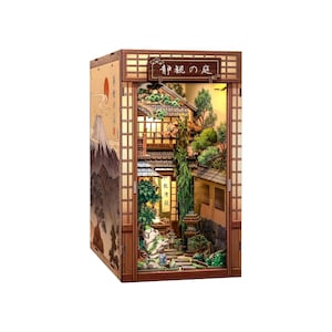 May include: A wooden book nook diorama featuring a Japanese garden scene with miniature trees, stone lanterns, and a building. The exterior side panel displays a mountain illustration. The top sign features the Japanese text "静観の庭".