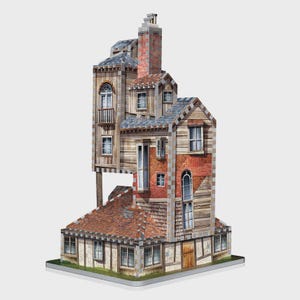 May include: A multi-story model house featuring a tall brick chimney, weathered wood siding, and a red tiled roof. The structure has an asymmetrical design with multiple windows, a small balcony, and a wooden door, all set on a flat base.