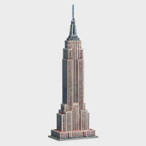 May include: A detailed architectural model of the Empire State Building, featuring a stepped, tiered design with a light tan and grey facade, numerous small window grid patterns, and a prominent central spire reaching toward the top.