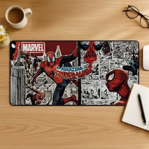 May include: A rectangular desk mat featuring a split design with a colourful Spider-Man illustration over a city skyline on the left and a black and white comic book panel collage on the right. The text MARVEL and THE AMAZING SPIDER-MAN are visible.