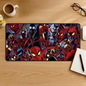 May include: A rectangular desk mat featuring a vibrant comic book style collage of various Spider-Man characters in red, blue, and black. The design is segmented by dark, angular lines, showcasing multiple versions of the hero in dynamic poses.