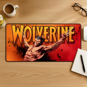 May include: A rectangular desk mat featuring a comic book illustration of Wolverine with his claws extended. The background is a gradient of orange and red with the word WOLVERINE printed in large yellow letters across the top centre.