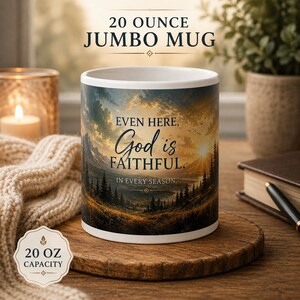 Op de afbeelding: Een witte 568 ml jumbo mok met een bedrukte landschapsillustratie van een bergketen bij zonsopgang met dennenbomen en de tekst: EVEN HERE, God is FAITHFUL. IN EVERY SEASON. De mok heeft een label met een inhoud van 20 oz.