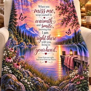 May include: A soft throw blanket featuring a sunset landscape with a lake, mountains, pine trees, flowers, and butterflies. The text reads: When you miss me, wrap yourself in warmth and smile, knowing that I am right there with you, living in your heart. Gone from our sight, but never from our hearts.