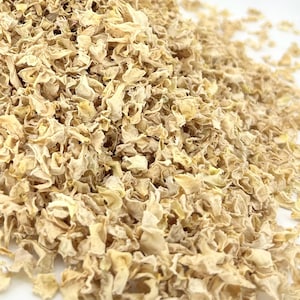 May include: A large pile of dried, light beige, shredded vegetable pieces with a crinkled, irregular texture. The individual fragments are thin, curled, and vary in size, creating a dense, textured mound of dehydrated plant matter.