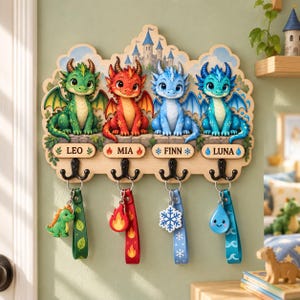 May include: A wooden wall-mounted hook rack featuring four colorful dragon illustrations labeled Leo, Mia, Finn, and Luna. Each dragon corresponds to a hanging keychain with matching motifs: a green dinosaur, a red flame, a white snowflake, and a blue water drop.