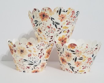 Op de afbeelding: Drie bloemen cupcakevormpjes met een geschulpte rand. De vormpjes hebben een crèmekleurige achtergrond met bloemen in aquarel-stijl in tinten oranje, geel en rood, samen met groene en grijze bladeren. Het ontwerp geeft een rustieke, herfstachtige uitstraling.