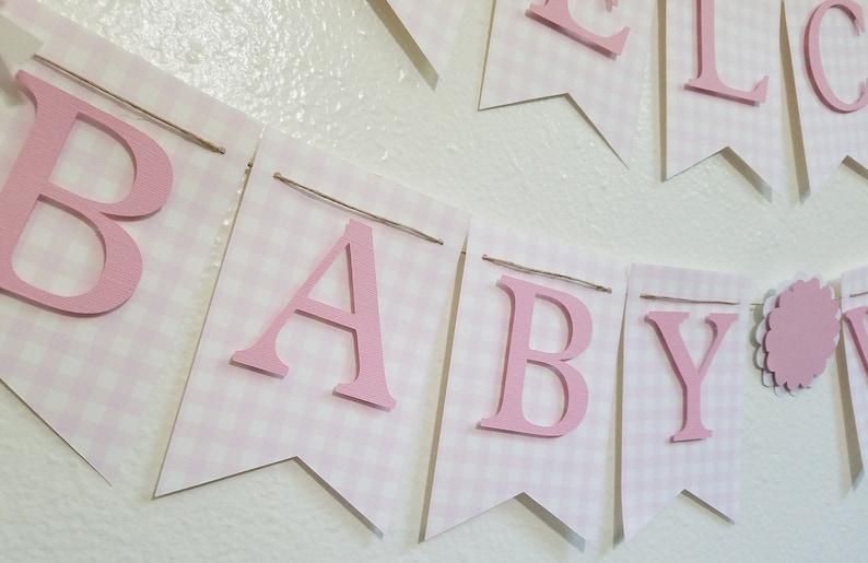 以下が含まれることがあります： ピンクと白のギンガムチェックのバナーで、ピンクの文字で「BABY」と書かれています。 バナーはひもでつながれており、ベビーシャワーや保育園の装飾用です。 文字は立体です。