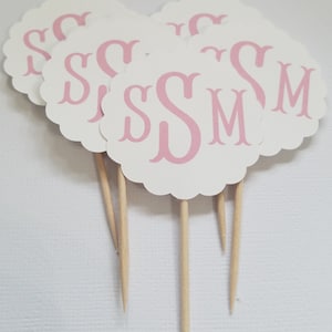 May include: Set of six white cupcake toppers with pink scalloped edges and pink monogram letters "SSM".