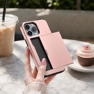 Könnte beinhalten: Eine roségoldene Smartphone-Hülle mit einem integrierten, verschiebbaren Kartenfach auf der Rückseite. Die Hülle verfügt über einen rechteckigen Ausschnitt für das Triple-Kamera-System und ein schwarzes Innenpanel unter der Schiebeabdeckung.