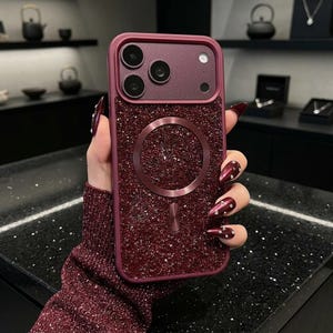 May include: A dark burgundy smartphone case featuring a textured, glittery back panel and a matching circular magnetic charging ring. The case includes a raised camera module with three circular lens cutouts and a smooth, solid-colored frame.