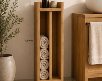 May include: A light oak towel organizer featuring a vertical shelf design with a top surface for accessories. The unit measures 800 mm in height, 300 mm in width, and 38 mm in thickness, constructed from 16 mm solid full stave oak.