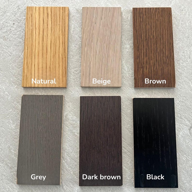 May include: Six rectangular wood veneer samples arranged in two rows. The top row features natural, beige, and brown finishes. The bottom row displays grey, dark brown, and black finishes. Each sample is labelled with its respective colour name.