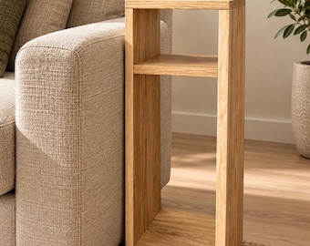 May include: A tall, narrow side table constructed from light-toned wood with a visible grain pattern. The piece features a rectangular frame with one horizontal shelf positioned in the upper section, creating an open storage space below.