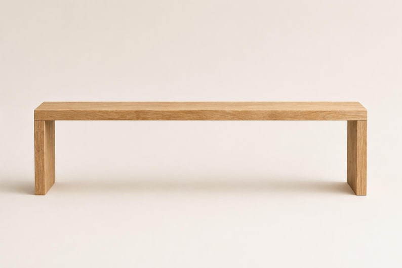 May include: A rectangular bench constructed from light-toned wood with a smooth, flat surface and two vertical side supports. The design features clean, straight lines and a natural wood grain pattern visible across the entire structure.