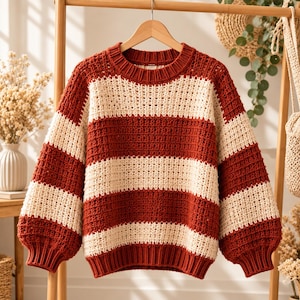 May include: A long-sleeved jumper featuring a horizontal striped pattern in alternating bands of rust orange and cream. The garment is constructed with a chunky, open-knit texture, a ribbed crew neckline, and ribbed cuffs at the wrists and hem.