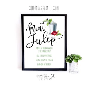 K&ouml;nnte beinhalten: Gerahmter Druck mit schwarzem Rahmen, der ein Mint Julep-Rezept in eleganter Schrift zeigt. Das Rezept enth&auml;lt Bourbon, Zuckersirup, Eis und Minze. Eine Aquarellillustration eines Cocktails, Minzzweige und eine rote Rose.