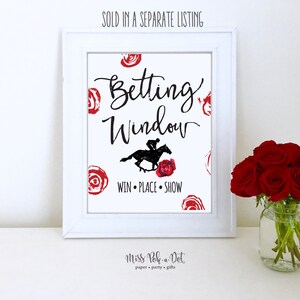 K&ouml;nnte beinhalten: Ein wei&szlig; gerahmter Druck mit den Worten "Betting Window" in schwarzer Schrift, einer Silhouette eines Jockeys auf einem Pferd und den Worten "Win, Place, Show". Rote Rosenakzente und der Text "Miss Pok-a-Dot" sind ebenfalls sichtbar.