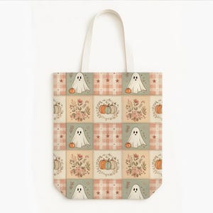 May include: A tote bag featuring a repeating patchwork pattern of ghosts, pumpkins, and floral arrangements in muted orange, green, and cream tones. The design includes checkered squares with small stars and ghost illustrations on a light background.