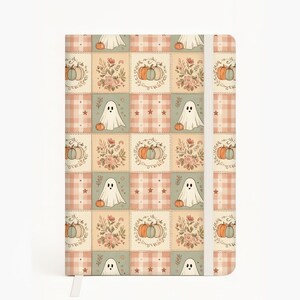 May include: A rectangular notebook featuring a repeating grid pattern of illustrations including white ghosts, orange and blue pumpkins, floral bouquets, and pink plaid squares. The notebook has a vertical white elastic band closure on the right side.