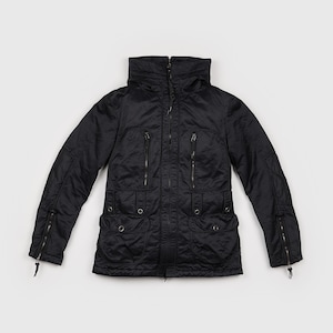 May include: A black long-sleeve jacket featuring a high collar, a full-length front zipper, and a hood. The garment includes two vertical zippered chest pockets, two lower flap pockets with snap buttons, and zippered cuffs on each sleeve.